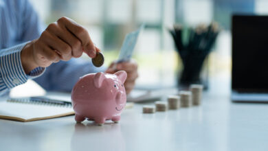 Hände eines jungen asiatischen Geschäftsmannes Mann legt Münzen ins Sparschwein und hält Geld nebeneinander, um Ausgaben zu sparen Ein Sparplan, der genug von seinem Einkommen für Zahlungen bereitstellt.
