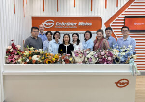 Das Team in Bangkok von Gebrüder Weiss steht versammelt hinter einer Theke.