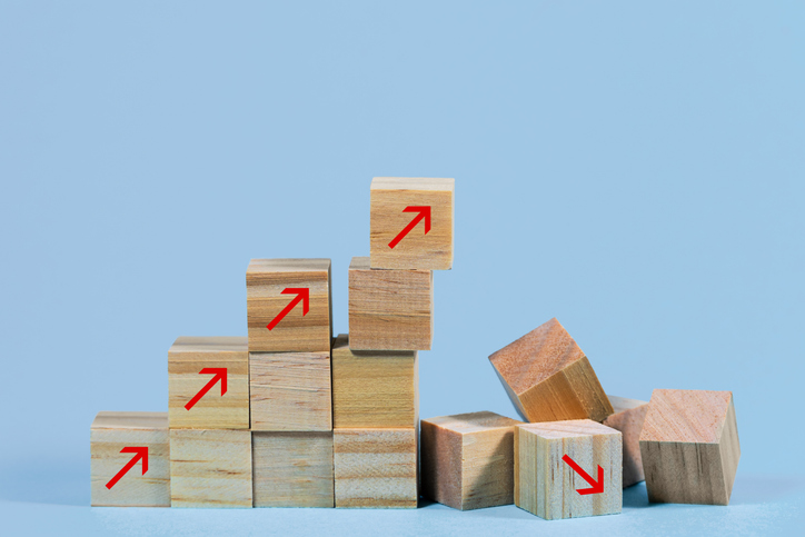 Eingestürzte Treppenstruktur aus Holzkuben mit nach oben zeigenden Pfeilen, Geschäftsrisiko aufgrund von Inflation, globaler Krise, Versorgungsengpass oder unhaltbarem Finanzkonzept, hellblauer Hintergrund