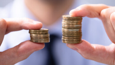 Man Holding Two Coin Stacks To Compare