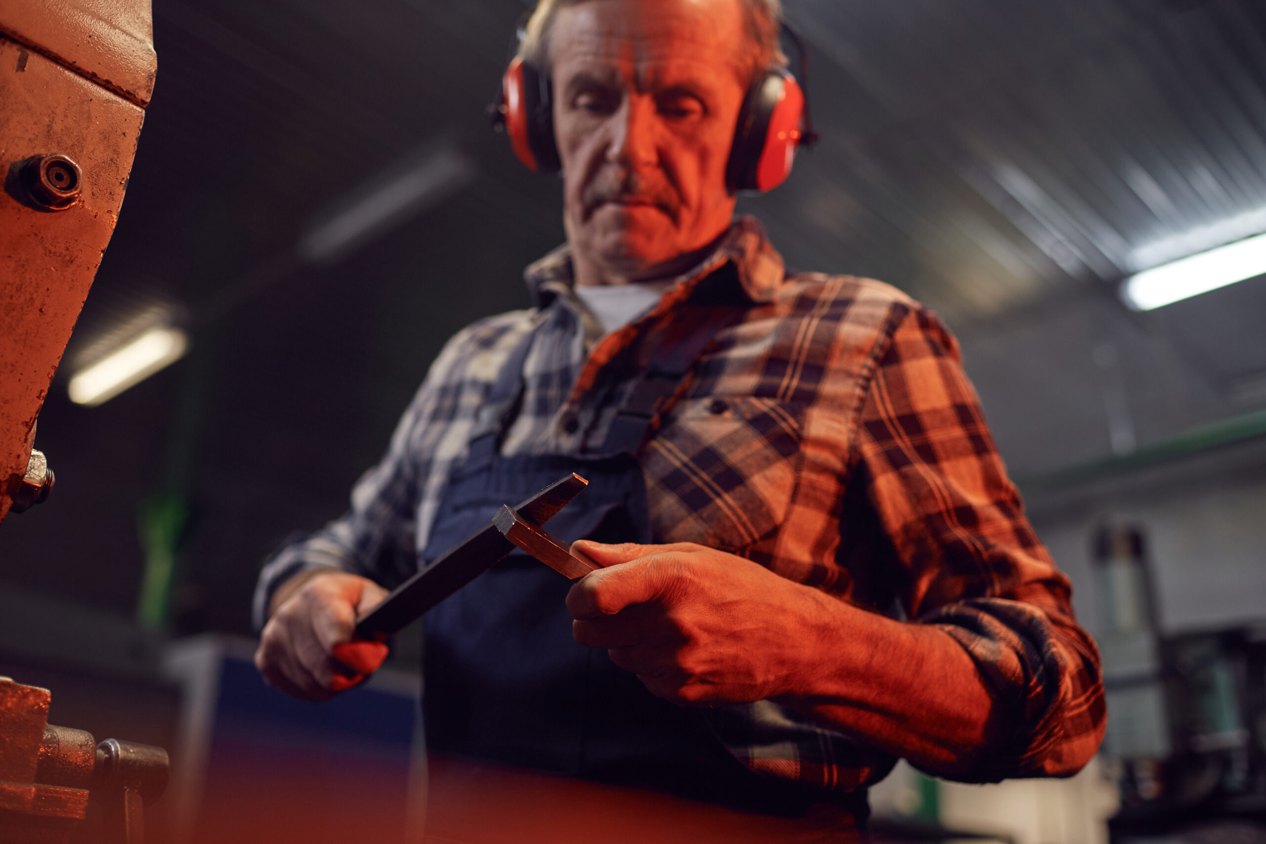 Serious senior worker in overalls standing and working with instruments in the factory AnnaStills (C) iStock GettyImages Plus