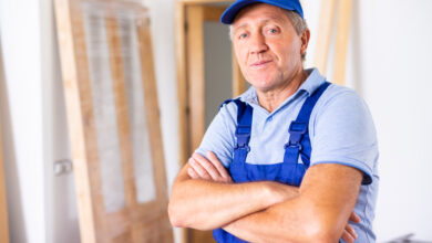 Portrait of a confident male builder in uniform looking at camera with crossed hands on chest during renovation at home