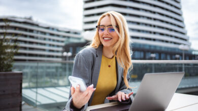 Young businesswoman remote working outdoors with laptop and phone