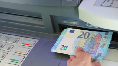 Hand of young person withdrawing twenty euros banknotes in a bank ATM in Europe